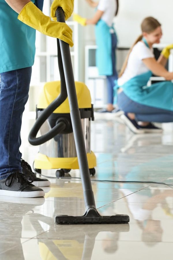 Janitor hoovering floor in office Janitor hoovering floor in office